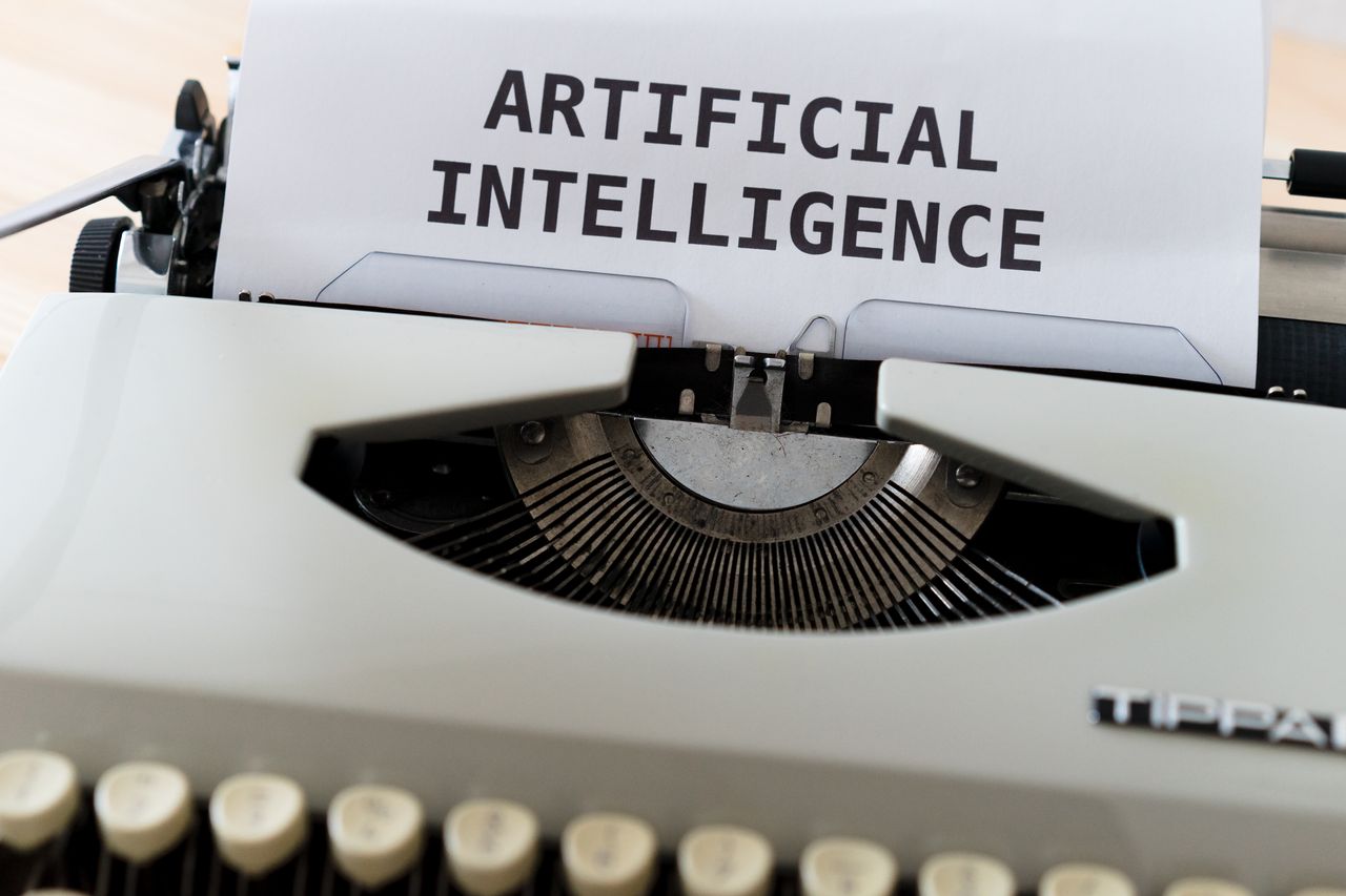 who-we-are A close-up of a typewriter showcasing 'ARTIFICIAL INTELLIGENCE' on paper.